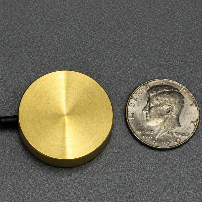 Enhanced brass large reel next to coin for scale