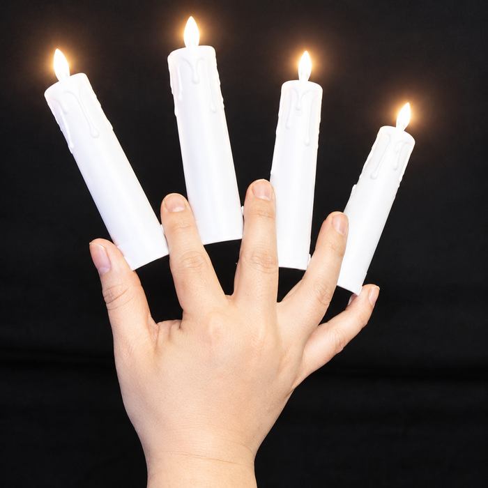Four lit multiplying candles held between fingers